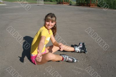 Girl sits on the floor with roller blades