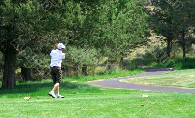 Lady golfer hitting ball across road