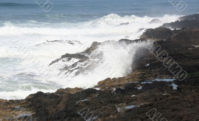 Surf breaking on volcanic rocks