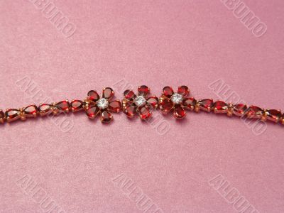 Jewelry bracelet with garnets on pink background