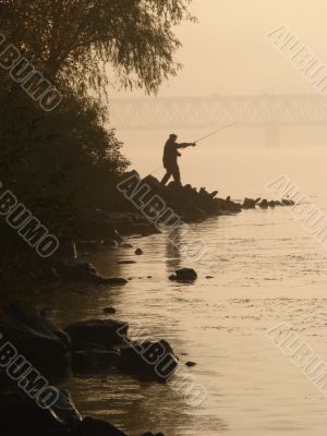 Silhuette of alone fisher near sunset river
