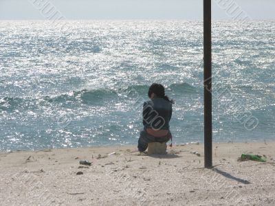 The girl in loneliness sits at sea coast