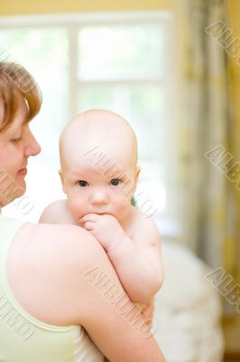 Mother holding baby. Baby put hand in your mouth