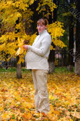 Pregnant woman in autumn park hold maple leaf #2 Pregnant woman in autumn park hold maple leaf #2