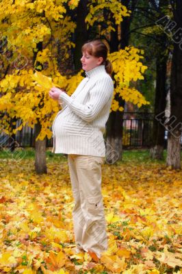 Pregnant woman in autumn park hold maple leaf #1
