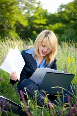Happiness woman on grass with laptop and documents