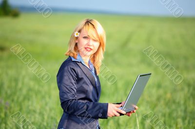 Girl with laptop stay on meadow