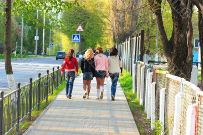 Four girls walking along the street. Rear view