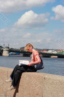 Girl reading magazine on canal border in Saint Petersburg