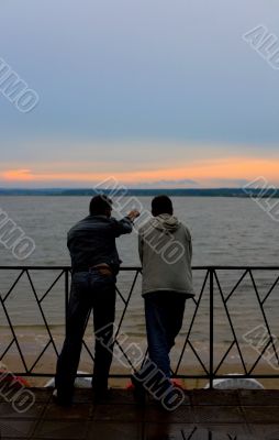 Two men on a river bay look at sunset #1
