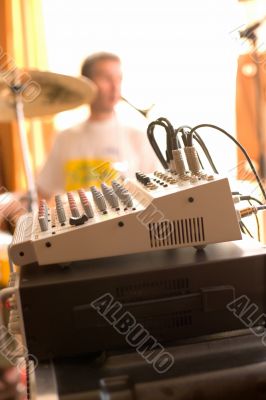 View on sound mixer board with drummer on background