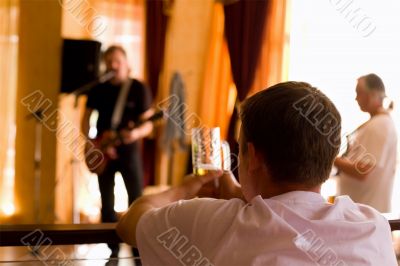 Man having beer and  look on playing band