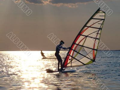 A women is learning windsurfing at the sunset