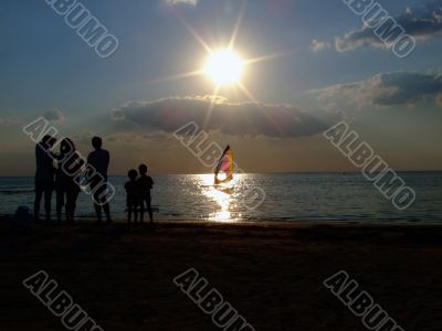 Silhouette of people looking at windsurf at sunset