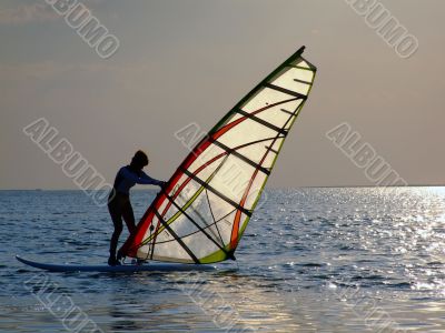 A women is learning windsurfing at the sunset