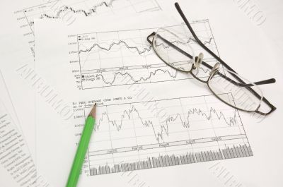 stock graphs, pencil and glasses