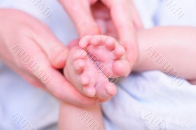 Mother hold baby leg in hand like shape of flower