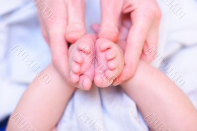 Mother hold baby leg in hand like rose flower