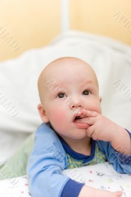 Baby on bed put fingers in mouth