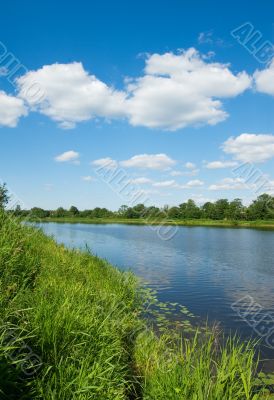 bank of the river, green grass and blue sky