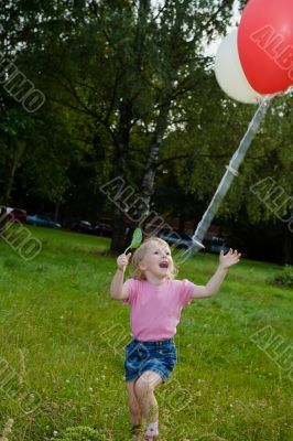 girl with balloon runs on lawn