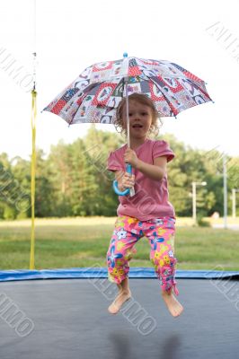 girl with umbrella jumping on trampoline
