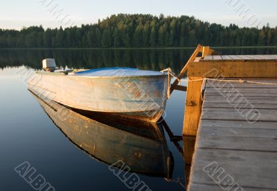 boat reflecting in calm waters of forest lake