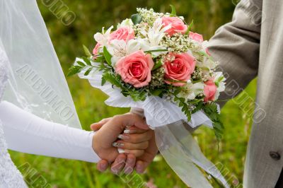 Wedding bouquet in hands of the groom and the bride