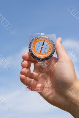hand with compass on background sky