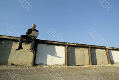Punk Businessman on a Wall with Laptop Computer