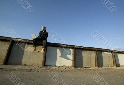 Punk Businessman on a Wall with Laptop Computer