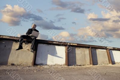 Punk Businessman on a Wall with Laptop Computer