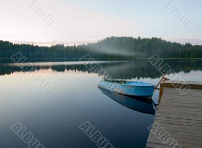 boat reflecting in calm waters of forest lake