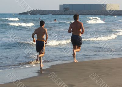 young men running on a beach