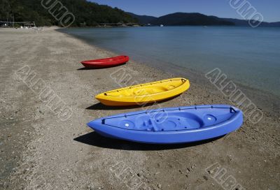 colorful kayaks on beach by turquoise waters