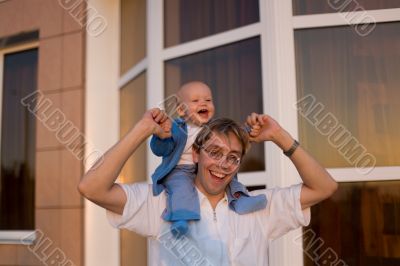 Adorable boy on his dad`s shoulders