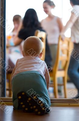 Little baby crawling through door aperture to parents on terrace