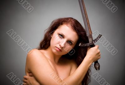 Attractive woman with sword on gray background