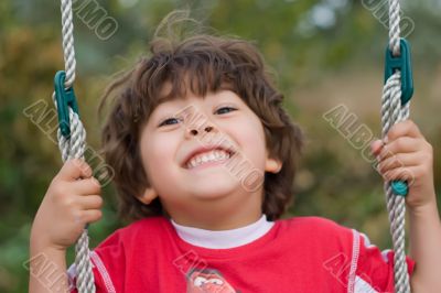 young boy swinging and smiling young boy swinging and smiling