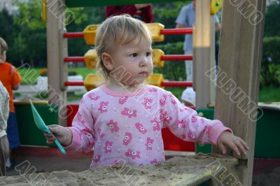 Toddler with shovel in sandbox