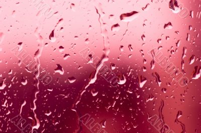 Flowing on transparent red glass water drops