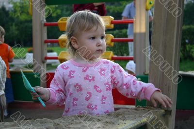 Toddler with shovel in sandbox