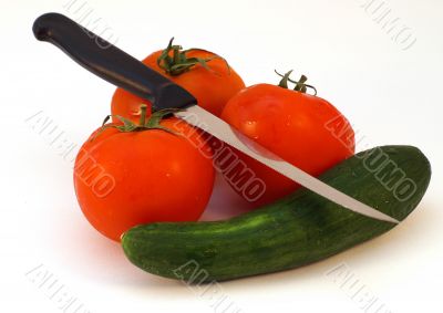 A knife and fresh vegetables tomato and cucumber