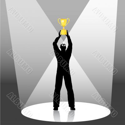 person holds trophy up in spotlight