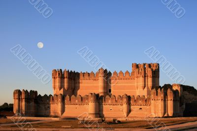 The fortress of Coca (Spain) at dusk with full moon