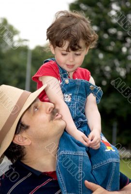 little girl is sitting on daddy`s shoulder