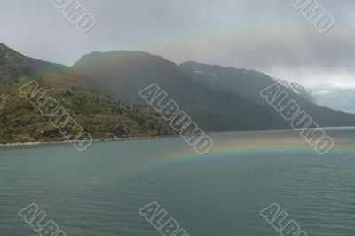 Rainbow, rocky hills and glacier