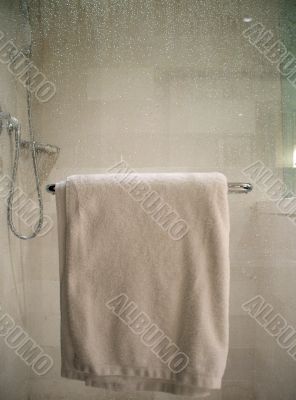 White Towel on Rack on Wet Glass Shower Door