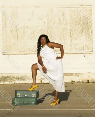African American woman with foot on suitcases