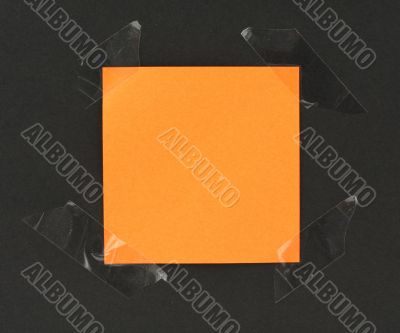 orange post-it stuck to a blackboard with tape